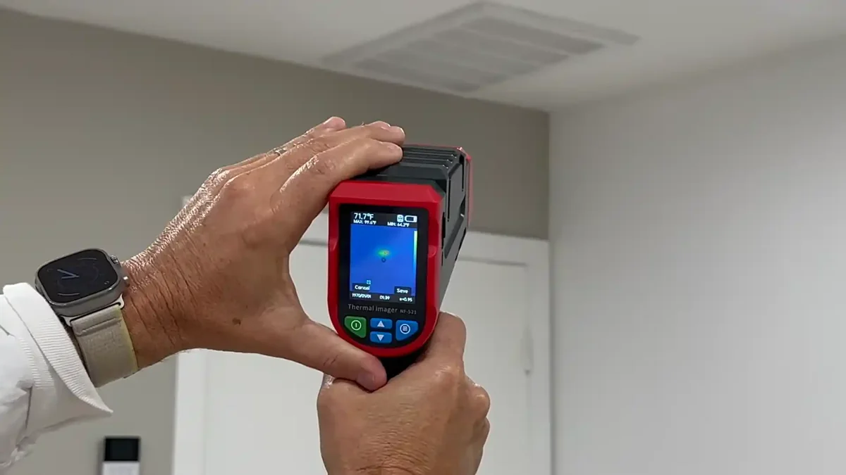 Leak detection technician using acoustic listening device on Boulder home floor, thermal camera nearby
