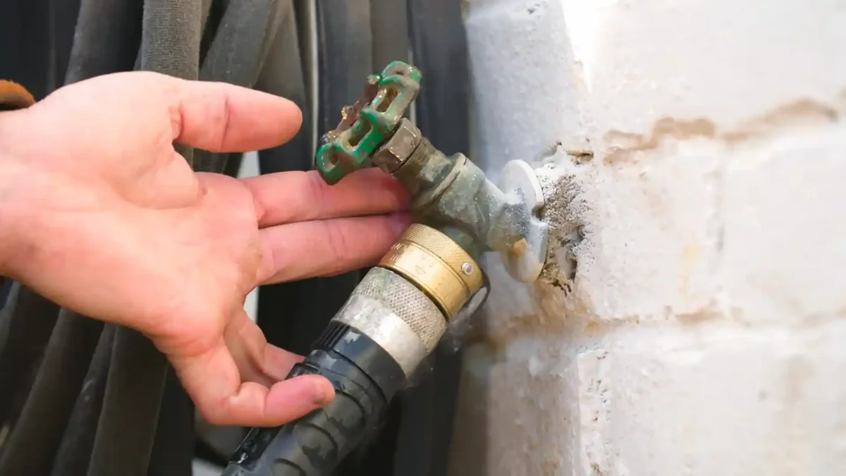 Frozen hose bib on Boulder Colorado home exterior with ice and garden hose attached