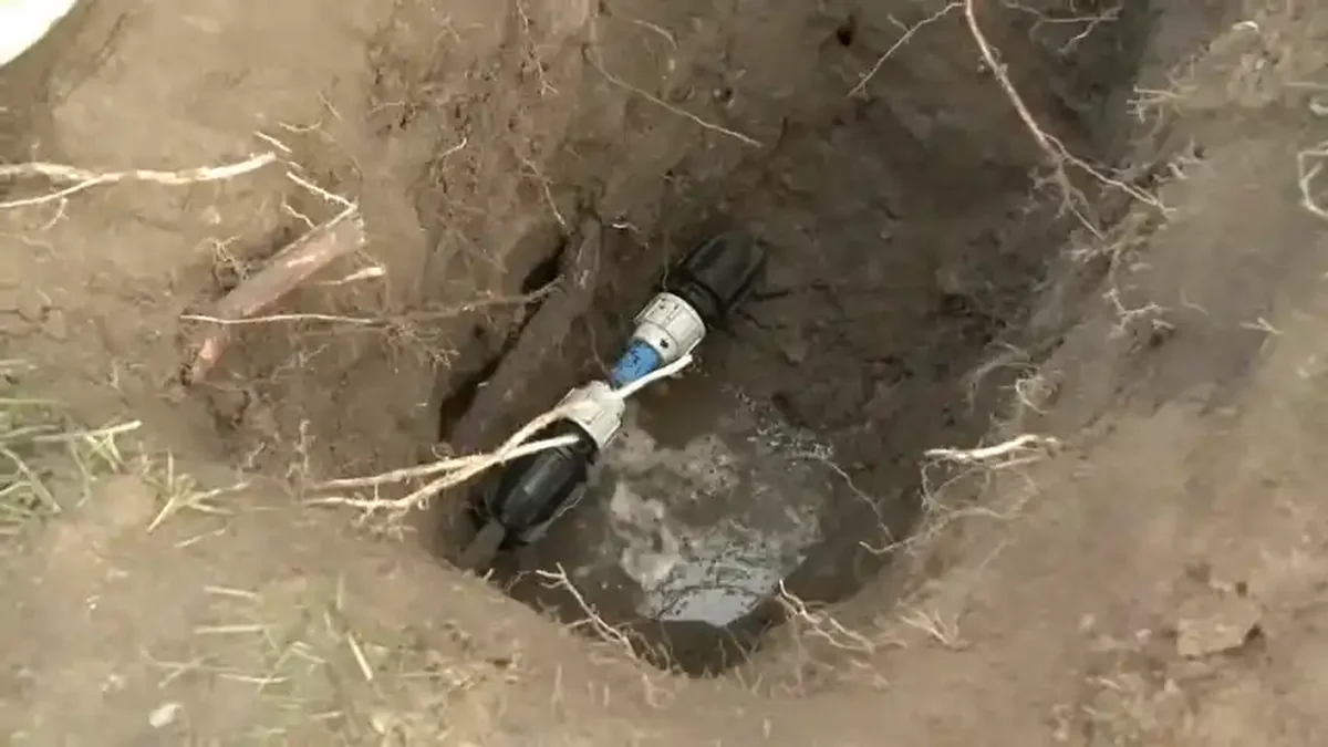 Boulder homeowner inspecting yard for signs of underground water line leak near meter box