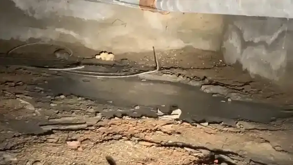 Boulder crawl space with moisture on subfloor joists, plumbing pipes visible above